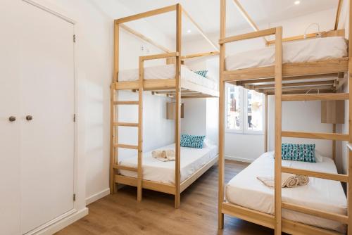 a bedroom with bunk beds in a room with wooden floors at Madalena Hostel e Suites in Faro