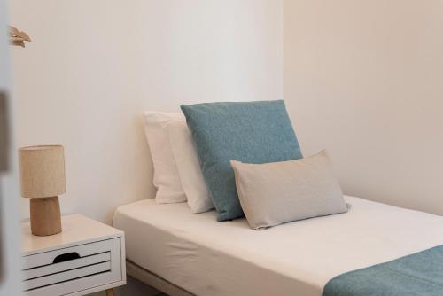a bed with blue and white pillows on it at Madalena Hostel e Suites in Faro