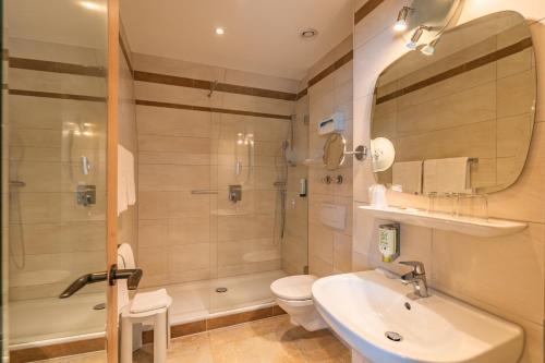 a bathroom with a sink and a toilet and a shower at Parkhotel Crombach in Rosenheim