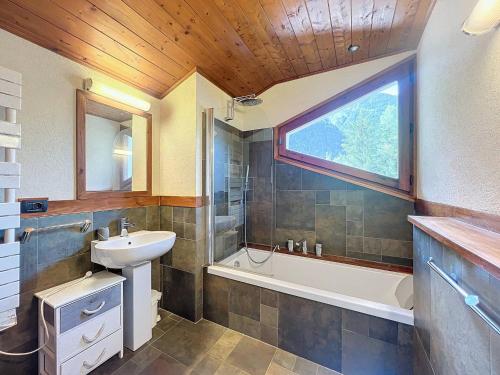 La salle de bains est pourvue d'un lavabo, d'une baignoire et d'une fenêtre. dans l'établissement Chalet de standing 4/6 pers, prox remontées, parking, non-fumeur - FR-1-507-32, à Chamonix-Mont-Blanc