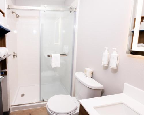 a white bathroom with a shower and a toilet at Microtel Inn & Suites by Wyndham Olean in Olean
