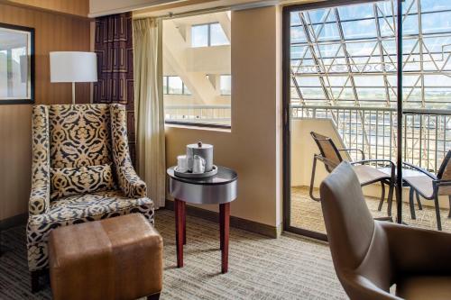 a room with a chair and a table and a balcony at Crowne Plaza Hotel St. Louis Airport by IHG in Bridgeton