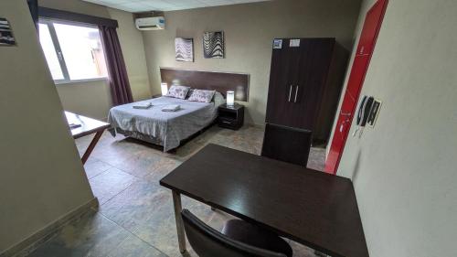 a hotel room with a bed and a desk and a table at Tres Arroyos Studio in Tres Arroyos