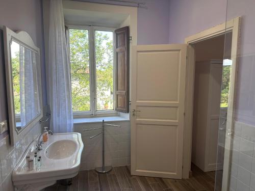 a white bathroom with a sink and a window at Paradiso verde in Lucca