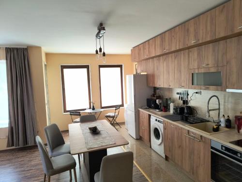 a kitchen with wooden cabinets and a table with chairs at Апартамент за гости Александър in Chepelare