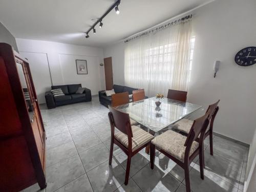 a dining room with a glass table and chairs at Apartamento VIP Centro Serra Negra - Familiar in Serra Negra