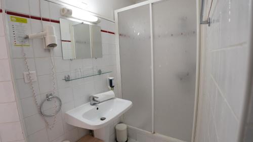 a white bathroom with a sink and a shower at Hotel Des Grands Hommes - Bordeaux Centre in Bordeaux