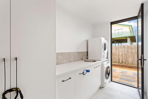 a white kitchen with a microwave and a washer and dryer at Upscale Family Retreat Just 5 Min Walk to Beach in Cape Woolamai