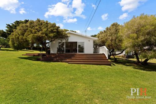 a white house with stairs and trees in a yard at Smith Beach Family House Sleep 6 in Smiths Beach