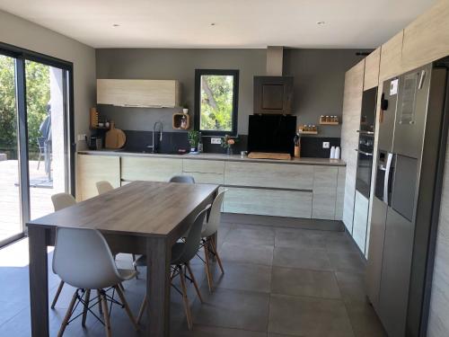 une cuisine avec une table en bois et quelques chaises dans l'établissement Location Maison contemporaine, piscine, 6-8 couchages, à Six-Fours-les-Plages