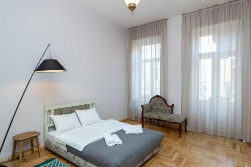 Un dormitorio con una cama y una silla y ventanas. en Stylish 2BR apt in the heart of old Tbilisi, en Tiflis