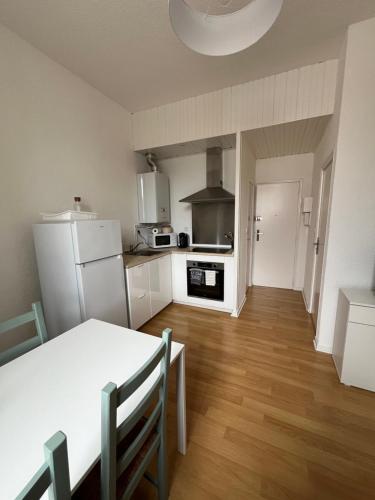 une cuisine avec une table et un réfrigérateur blanc dans l'établissement Appartement en centre ville, à Hendaye