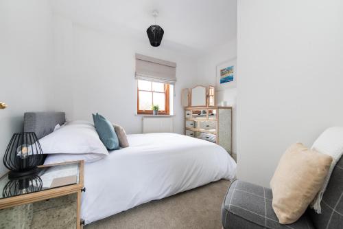 a bedroom with a white bed and a chair at Hideaway Cottage Bewdley with parking near the River Severn in Bewdley