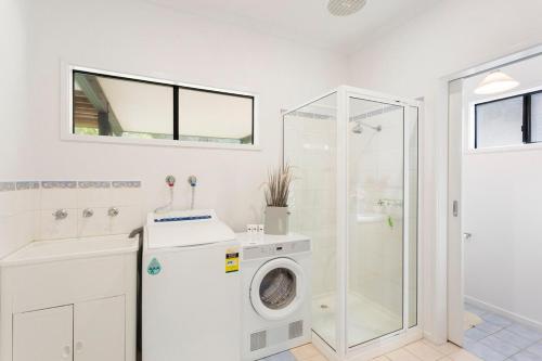 y baño blanco con lavadora y ducha. en Serene Modern Beach Escape 3 Bed 2 Bath, en Cape Woolamai