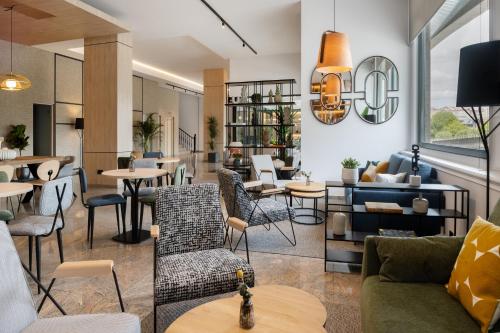a living room with tables and chairs and a couch at Hotel Santiago Plaza Affiliated by Meliá in Santiago de Compostela