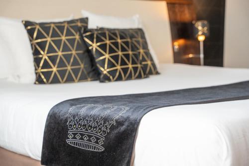 a bed with black and white sheets and pillows at Mercure Le Mans Centre in Le Mans