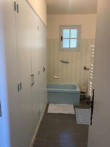 La salle de bains est pourvue d'une baignoire bleue et d'une fenêtre. dans l'établissement Villa entière à 550 m du centre-ville, à Valensole