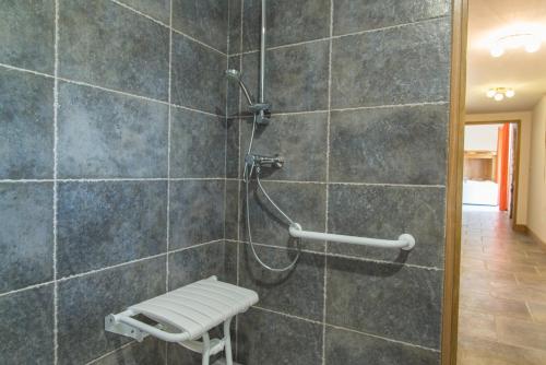 a bathroom with a shower with a bench in it at L'etable de pierre in Nojaret