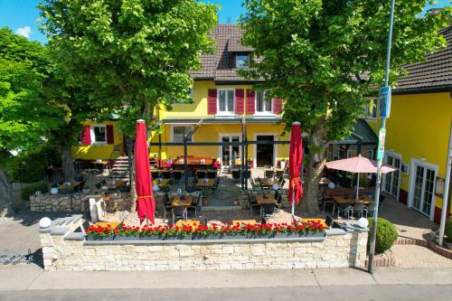 a restaurant with red umbrellas and flowers in front of a building at Tuniberg Restaurant Hotel in Freiburg im Breisgau