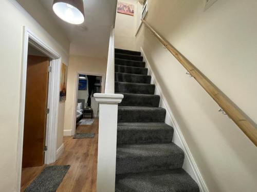 a staircase in a home with a gray carpet at Serenity Luton Suite Near Mall in Luton