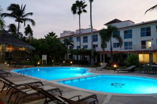 a large swimming pool with chairs and a hotel at Beautiful house in secure subdivision in Acapulco