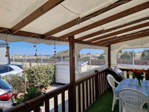 terraza de madera con mesa y sillas en el porche en Camping le castellas L151, en Mèze