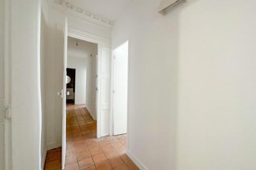 un couloir vide avec des murs blancs et du carrelage dans l'établissement Flexliving - room - Echiquier, à Paris