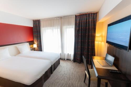 a hotel room with a bed and a desk with a laptop at Mercure Le Mans Centre in Le Mans