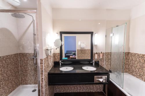 a bathroom with two sinks and a shower and a mirror at Mercure Le Mans Centre in Le Mans