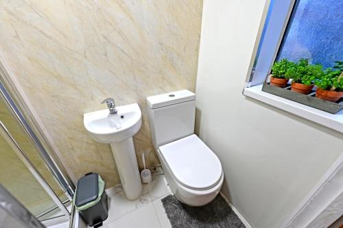 a bathroom with a toilet and a sink and a window at Exclusive Ensuite Escape near the Mall in Luton
