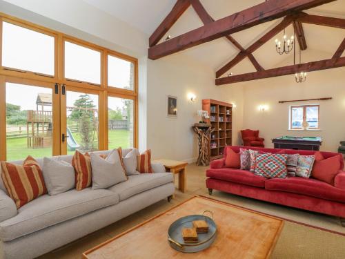 a living room with two couches and a red couch at Lower Farm Barn in Oxford