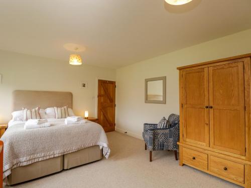 a bedroom with a large bed and a wooden cabinet at Lower Farm Barn in Oxford