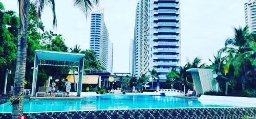 a large swimming pool in a city with tall buildings at Studio Seaview Jomtien floor12 23sqm in Jomtien Beach