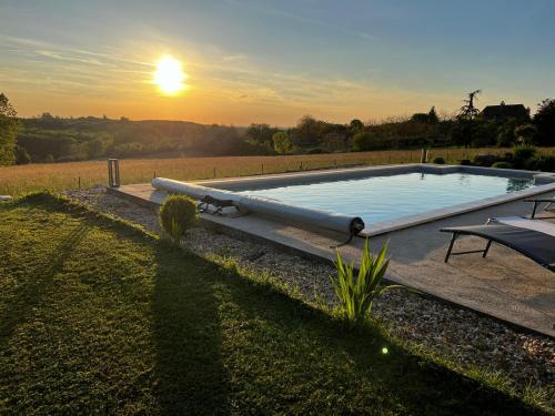 una piscina con puesta de sol en el fondo en Villa coucher de soleil, en Pontours