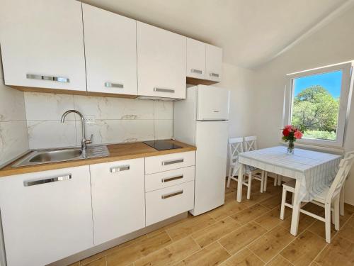 a kitchen with white cabinets and a table and a window at Holiday Resort Balota in Viganj