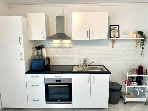 une cuisine avec des armoires blanches et un évier dans l'établissement Au Coeur du Quartier Taittinger, à Reims