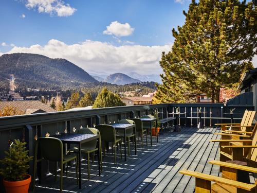 a deck with tables and chairs and mountains at The Outpost Rocky Mountains in Estes Park