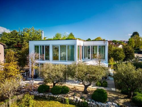 a house with a lot of windows and trees at Villa Serenity Sustainable Luxury Retreat by GuestLee in Preverenges