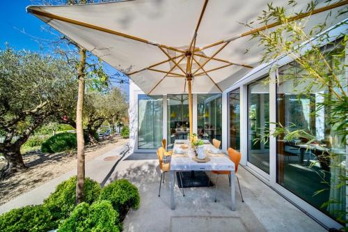 a dining room with a table and an umbrella at Villa Serenity Sustainable Luxury Retreat by GuestLee in Preverenges