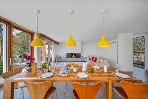 a dining room with a wooden table and yellow lights at Villa Serenity Sustainable Luxury Retreat by GuestLee in Preverenges