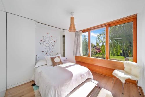 a bedroom with a bed and a window and a chair at Villa Serenity Sustainable Luxury Retreat by GuestLee in Preverenges