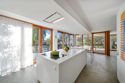 a kitchen with a white island in a room with windows at Villa Serenity Sustainable Luxury Retreat by GuestLee in Preverenges