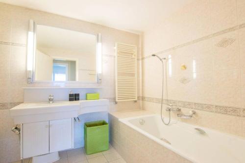 モントルーにあるAlpine Stunning Apartment in Montreux by GuestLeeの浴槽、洗面台、鏡のあるバスルーム