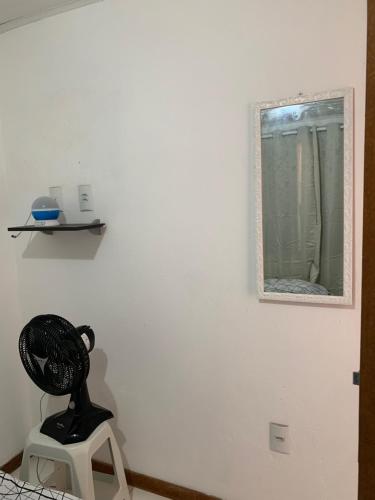 a mirror on a wall with a statue on a stool at Suite da Paty in Praia do Forte