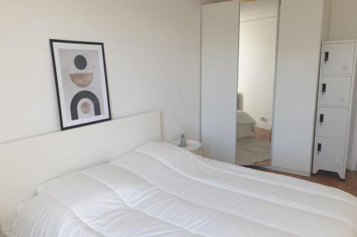 - une chambre blanche avec un lit blanc et un miroir dans l'établissement Flexliving - room - Voltaire, à Paris