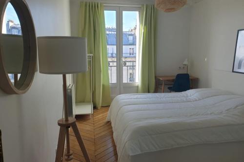 une chambre avec deux lits, un miroir et une fenêtre dans l'établissement Flexliving - room - Voltaire, à Paris