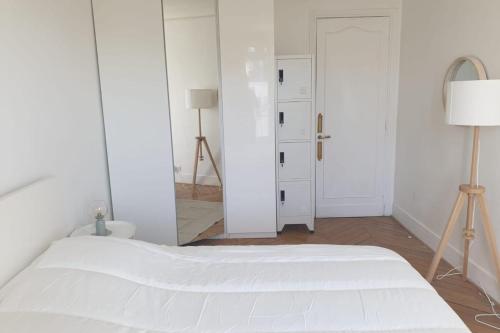 - une chambre blanche avec un lit blanc et un miroir dans l'établissement Flexliving - room - Voltaire, à Paris