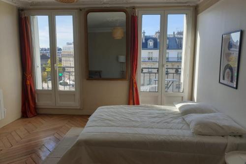 une chambre avec un lit et de grandes fenêtres dans l'établissement Flexliving - room - Voltaire, à Paris