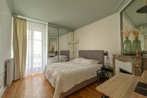 une chambre avec un lit et un grand miroir dans l'établissement Flexliving - room - Bachaumont, à Paris