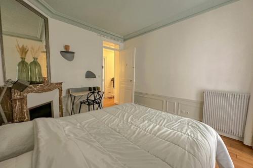 - une chambre avec un lit blanc et une cheminée dans l'établissement Flexliving - room - Bachaumont, à Paris